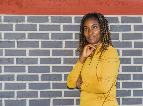Young black woman in yellow with curly hair posing against a brick wall, Taken in Daejeon, South