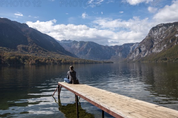 Sitting on a small jetty and enjoying the view on the landscape of lake Bohinj in the Triglav