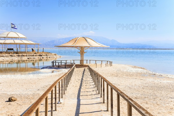 Lovely round umbrella protects from the sun. The drainless salt lake in the Middle East. Dead Sea.