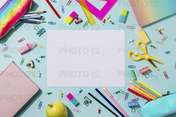 Creative student desk with empty white sheet and colorful modern school supplies on blue background