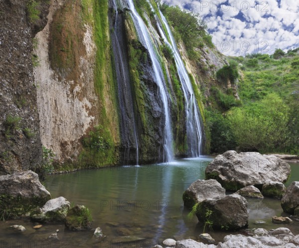 Three parallel streams of water running down the steep slope and fall in oval pool. Three-jet