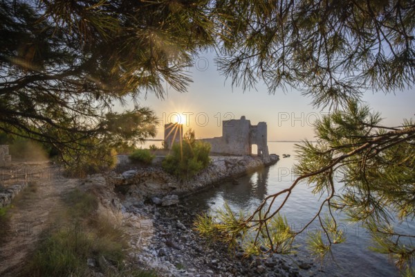 Sunrise on a rocky coast. Reflection in the calm water. Landscape shot of the restored remains of