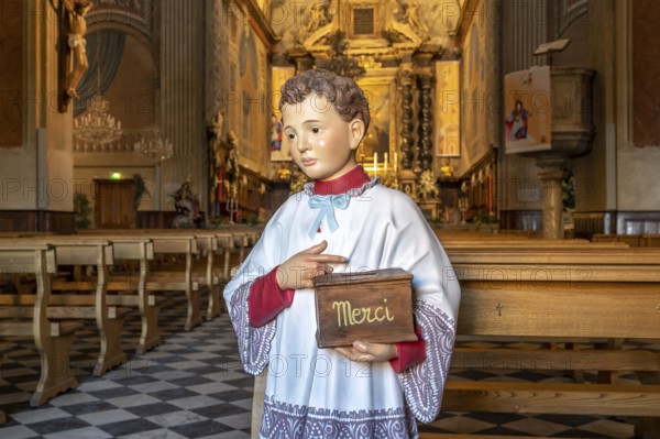 Altar boy sculpture with Merci donation box for the collection in the Catholic Cathedral Notre-Dame