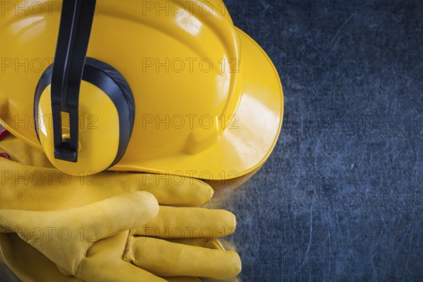 Hard hat ear muffs and leather protective gloves on metallic background close up view construction