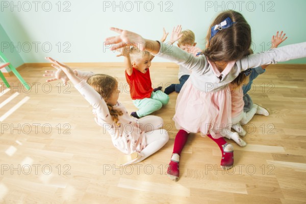 Kids with irresistable joy playing on a wooden floor at the preschool. Children full of fun and