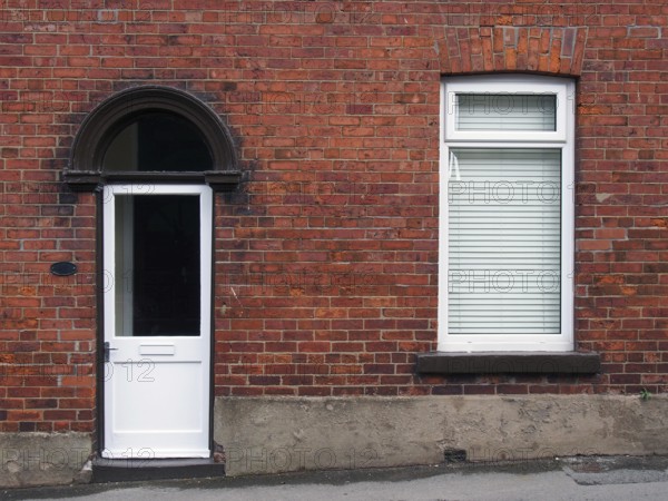 White front door and window of a typical old brick british terraced house with white windows and