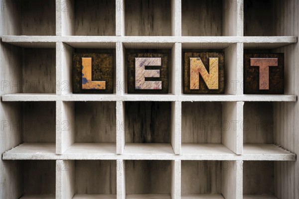 The word LENT written in vintage ink stained wooden letterpress type in a partitioned printer's