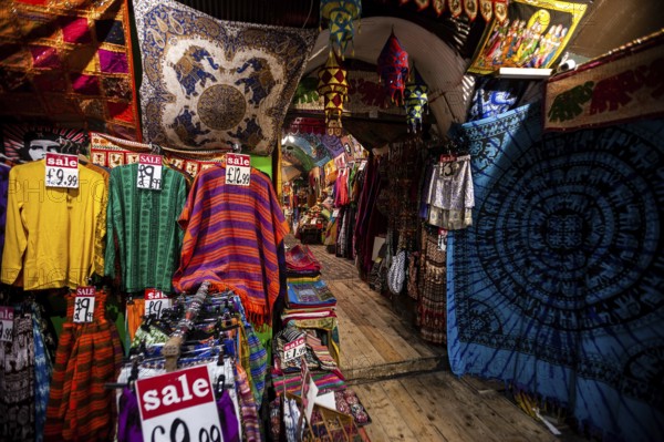 Colorful garments and textiles with sale signs in a vibrant market setting in the London Borough of