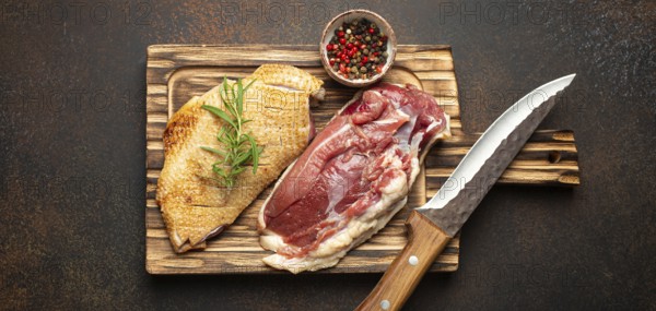 Two raw uncooked duck breast fillets with skin, seasoned with salt, pepper, rosemary top view on