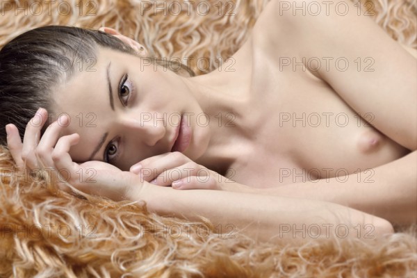Beautiful naked woman laying on a fur. Torso portrait with naked breast