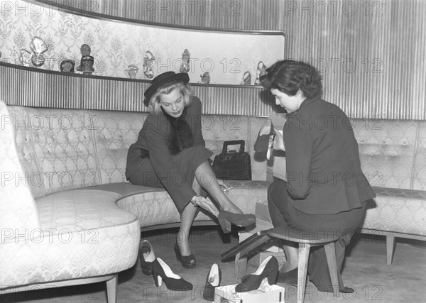 A young woman is well taken care of by a clerk in a shoe store. The dispatcher tries different
