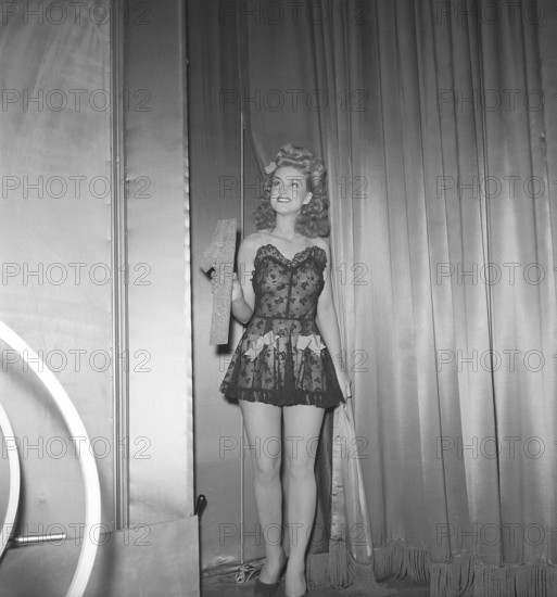 At the theatre in the 1940s. A young woman holds the number one in her hand on a theatre stage. It