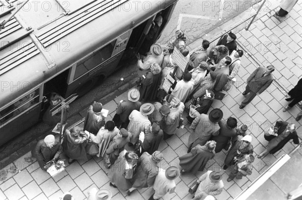 Bus stop in Stockholm in 1953. People are waiting for the bus at the bus stop. Bus 32 travelling on