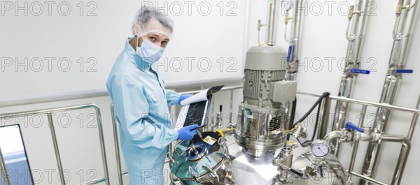 Widescreen picture, scientist in blue laboratory suit and gas mask stand in clean room and check