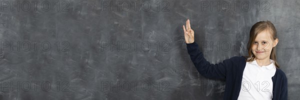 Schoolgirl shows on an empty school board. He is standing in the classroom at the chalkboard.