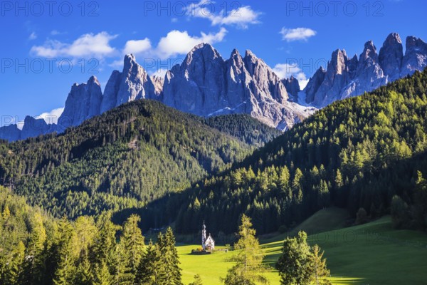 Dolomites, Tirol. Sunny autumn day. Rocky peaks and forested mountains surrounded by green Alpine