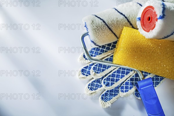 Safety gloves paint rollers on white surface