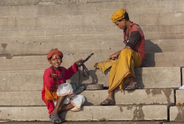 Children with cobra at ghat steps on river Ganges, Varanasi, Uttar Pradesh, India