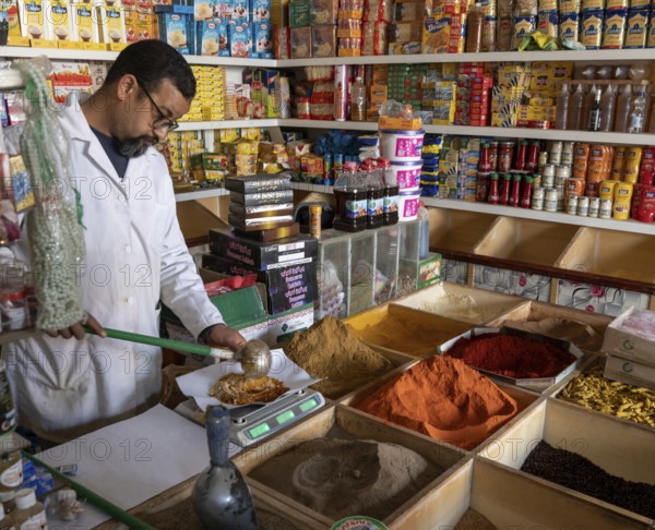 Er-Rich, Morocco, 7 March, 2024: Moroccan shopkeeper mixing spices in his shop in the market of