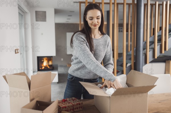 Young caucasian woman wrapping a gift, getting it ready to send in the post. Woman packaging a