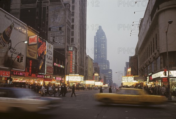USA New York 1967. Broadway in the evening with cars and people visible and signs on all the