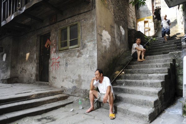 04.08.2012, Chongqing, China, Asia, Men sit on the steps in front of a house in the old town of
