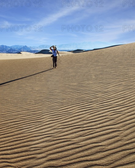 USA. Mesquite Flat Sand Dunes, Death Valley, California. Woman with a camera and a tripod goes