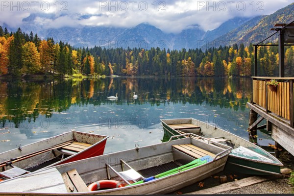 The boat dock. The Lago Fusine in Italy. The bright colors of the autumn forests are reflected in