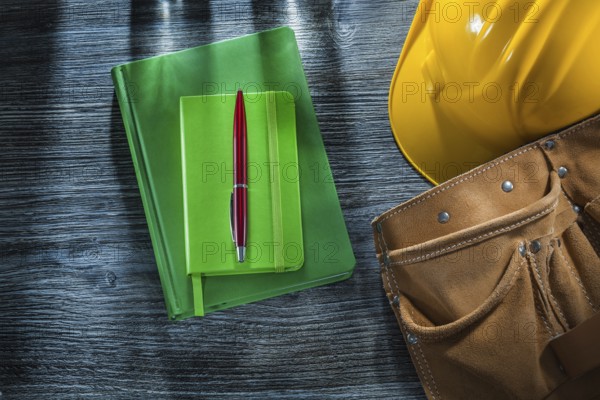 Notepads pen hard hat tool belt on wooden board
