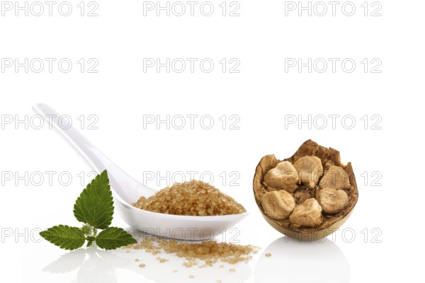 Heap of brown cane crystallized sugar in white spoon and monk fruit, luo han guo isolated on white