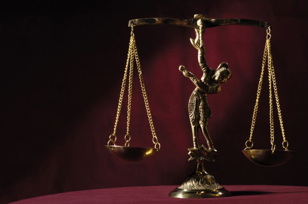 Stock photo of Shiny golden empty balanced vintage justice scales isolated on dark red background