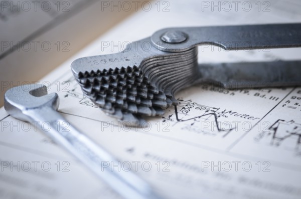 Detailed view of a fanned-out thread gauge with a small spanner lying next to it on an old