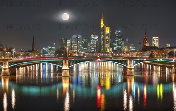 The illuminated skyline of the city centre of Frankfurt am Main at night and full moon with the