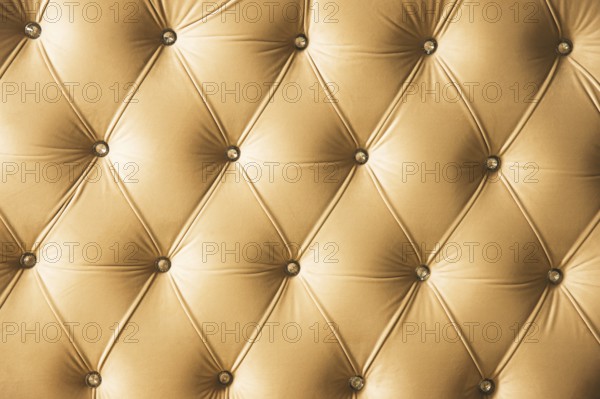 Beige soft textile background with symmetrical buttons on the corners of diamonds. Soft and