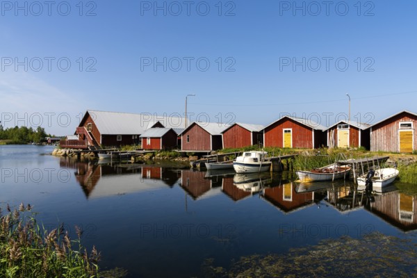 Svedjehamm, Finland - 28 July, 2021: colorful fishing cottages and boats reflected in the water