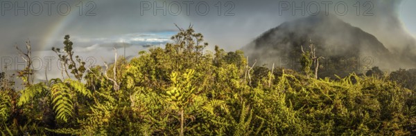 Panoramic photo of mountains covered by fog with rainbow in Digne in Kubor range, Papua New Guinea.