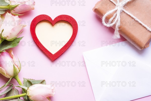 Valentine day theme image with a red heart with copy space in the middle, surrounded by pink roses,