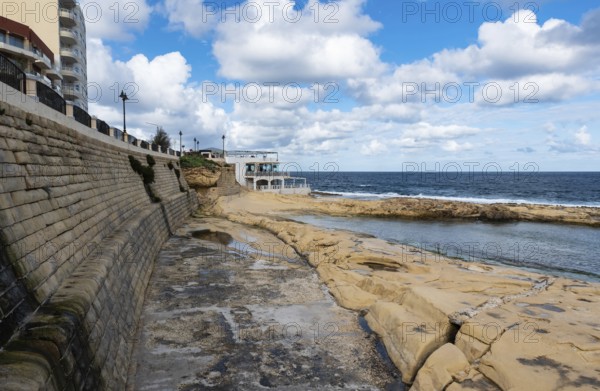 Saint Julian, Malta, 01 07 2022: Low angle view over the water, rocks and sand at the beach with
