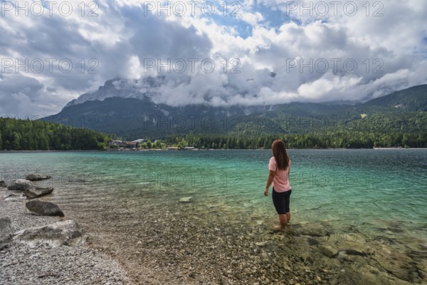 Zugspitze Peak top of Germany Alps mountain range and Eibsee Lake with woman tourist, Garmisch