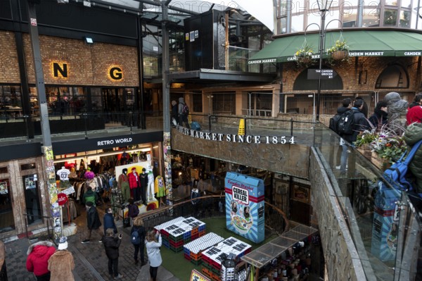 Shoppers at an elevated outdoor market with clothing stores and signs in the London Borough of