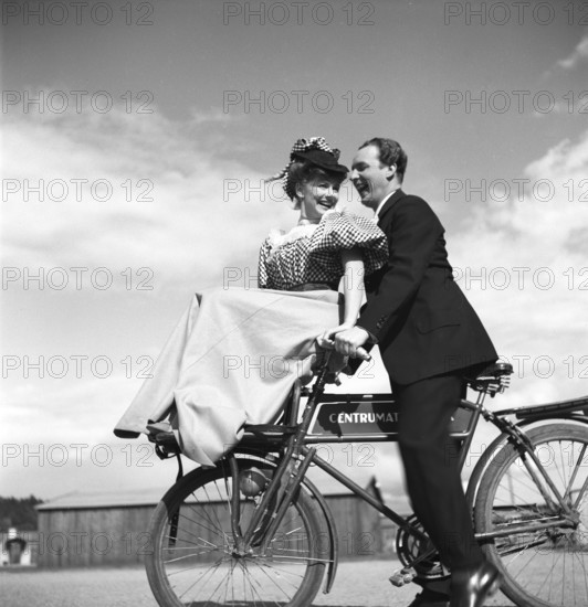 1940s couple on a bicycle. A young couple is riding their bicycles on a sunny day. They are both