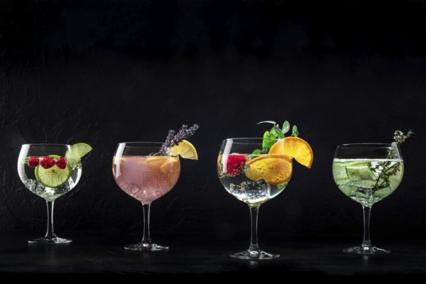 Fancy cocktails with fresh fruit. Gin and tonic drinks with ice at a party, on a black background,