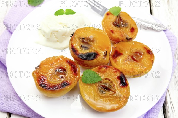 Five halves of quince baked with honey, ice cream and fork in a plate on a lilac napkin on a wooden