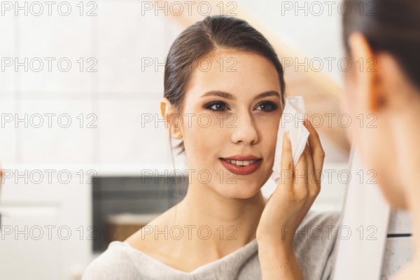 Beautiful young woman cleaning her face, removing make up with a cotton pad and micellar water.