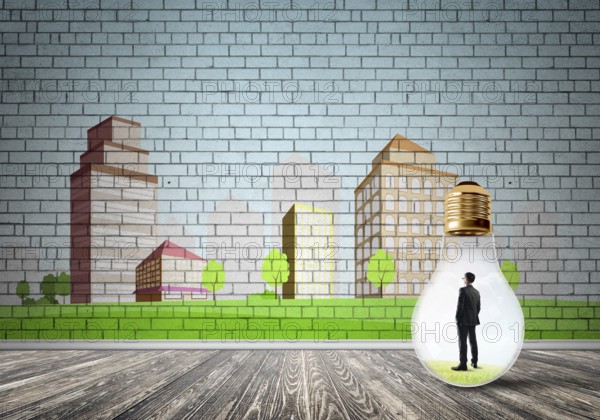 Businessman inside light bulb against city drawn concept