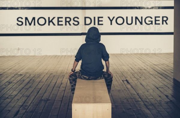 Teenager smoking and message on wall - Smokers die younger. No smoking concept with child. Casual