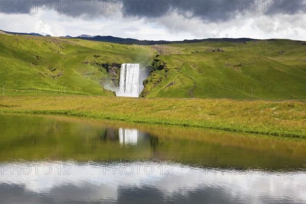 An incredible reflection. Abounding waterfall Skogafoss reflected in a small pond near the road