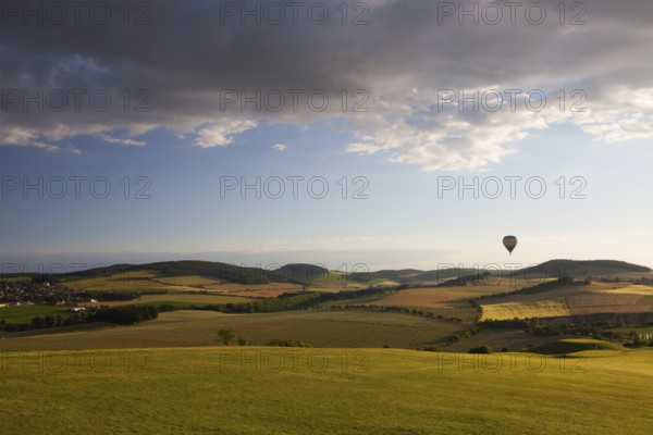 Hot air balloon flying over a golf course and amazing valley at sunset