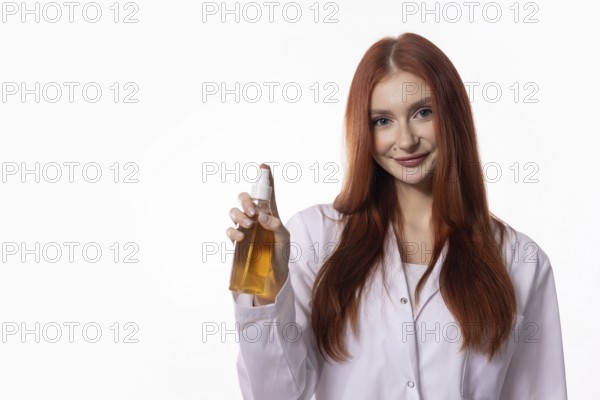 A confident woman in a lab coat showcases a nourishing oil in a professional setting, exuding