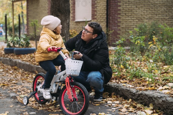 Father with daughter learning to ride the bike. Autumn weekend day in the city neighbourhood.